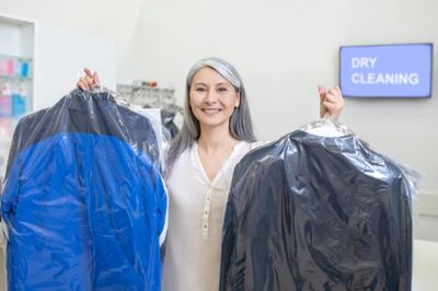 women holding dry cleaning clothes