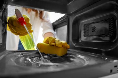 women cleaning oven with solution