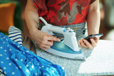 women setting iron temperature by checking on mobile