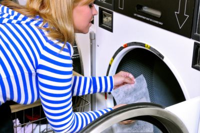 laundress adding dryer sheet in the dryer